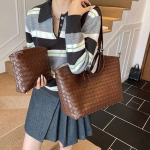 Close-up of brown woven leather tote bag set with matching pouch in soft lighting