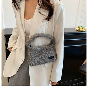 Close-up of grey plush handbag featuring a silver chain and minimalist brand label
