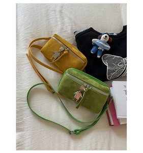 Detail of yellow and green suede crossbody bags with cute robot metal charms