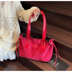 Detail of red matte suede tote bag featuring silver hardware and side tassel drawstring