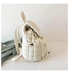Detail view of cream quilted backpack featuring puffy fabric and drawstring closure side