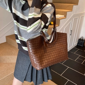 Detail of dark brown woven leather tote bag showing intricate intrecciato craftsmanship