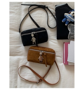 Detail of vintage suede crossbody bags in black and caramel with robot metal charm