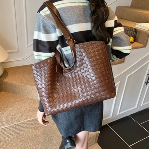 Detail of a large brown tote bag featuring a premium intrecciato weave leather texture