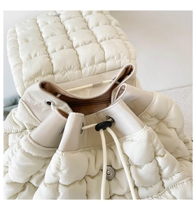 Close-up of quilted puff backpack with drawstring closure and metal magnetic buckle