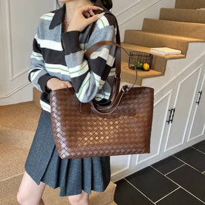 Brown woven leather tote bag shown in a lifestyle setting with stylish knitwear