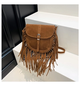 Dettaglio della borsa a sella in pelle scamosciata marrone con frange e cuciture boho