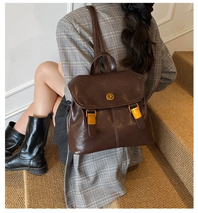 Detail of vintage dark brown PU leather backpack with gold clasp on a model