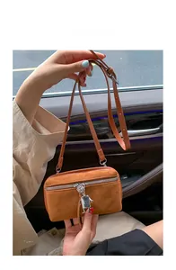 Detail of brown suede crossbody bag with a cute silver robot zipper pull charm