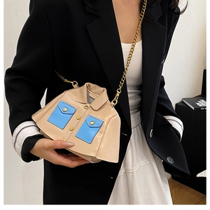 Mini beige jacket-shaped crossbody bag with blue pockets and gold chain strap shown on model