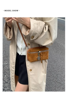 Close-up of brown suede textured crossbody bag featuring silver robot charm and zipper