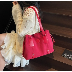 Detail of red matte leather tote bag featuring side drawstrings and metallic studs