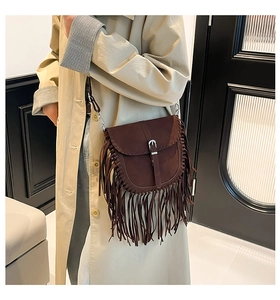 Dettaglio della borsa a sella in pelle scamosciata marrone scuro con lunghe frange