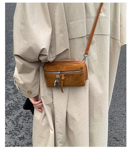 Close-up of brown suede mini crossbody bag with a unique silver robot charm accessory
