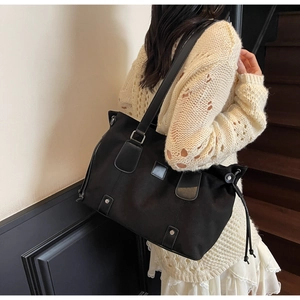 Detail of black canvas tote bag with PU leather straps and side drawstring on stairs