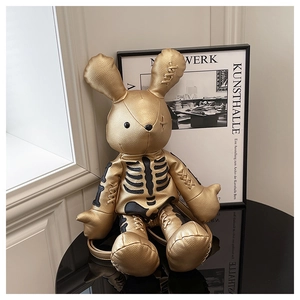 Detail of a gold metallic rabbit backpack with black skeleton print and PU leather texture
