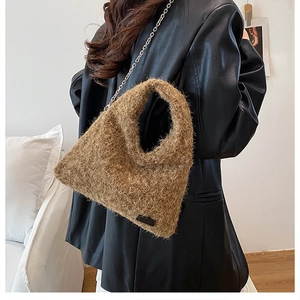 Detail of plush dark brown faux fur handbag with silver chain strap and round handle