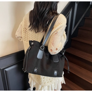 Detail of black matte tote bag featuring silver rivets and elegant drawstring tassels