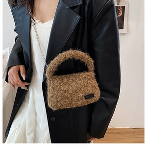 Detail of soft brown faux fur texture and silver chain strap on a plush handbag