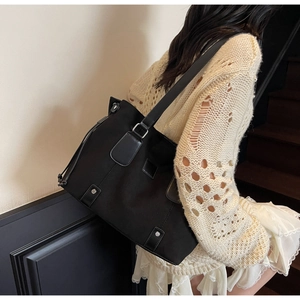 Close-up of black matte tote bag with leather straps and drawstring detail on model