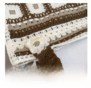 Detailed macro view of bohemian knit handbag featuring crochet floral patterns and button