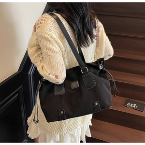 Close-up of a large black canvas tote bag with leather handles and silver studs detail