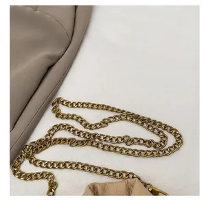 Details einer Vintage-Goldkette und eines Karabinerverschlusses an einer beigen Tasche