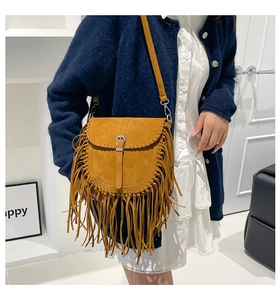 Dettaglio borsa a sella bohémien con frange giallo zenzero e bordi intrecciati sulla tracolla