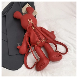 Detail of red leather doll-shaped backpack with gold hardware and pebble texture