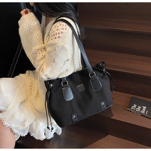Close-up of a black canvas tote bag with drawstring detail and leather trim for daily commute