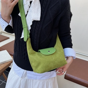 Sac hobo en daim vert avec bandoulière en cuir porté par un mannequin en extérieur