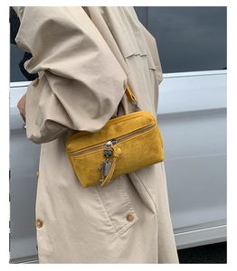 Detail of mustard yellow suede crossbody bag with silver robot charm and zipper
