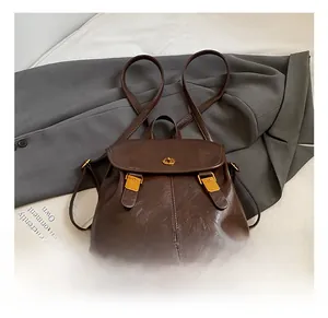 Detailed close-up of a vintage dark brown leather backpack with gold buckle on a blazer