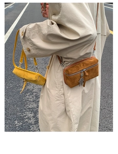 Close-up of mini suede crossbody bags with silver robot charms on a stylish street
