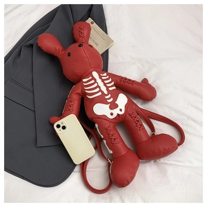 Detail view showing small red rabbit backpack with skull pattern next to a phone for scale