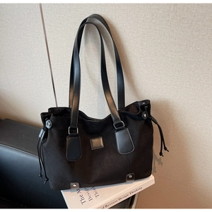 Detail view of black tote bag with matte texture, side drawstrings and rivet accents