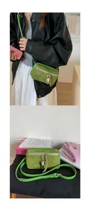 Detail of green suede crossbody bag with silver zipper and robotic charm accessory