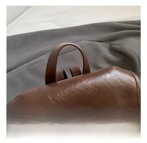 Detail of dark brown faux leather backpack handle and vintage brass clock ornament