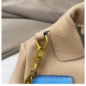 Detail of gold metal buckle and chain on beige pleated leather crossbody bag