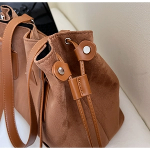 Close-up of brown suede fabric with leather drawstring and silver metal eyelet detail