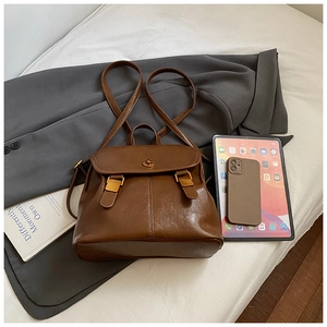 Detail of vintage brown PU leather backpack with gold twist lock and dual strap buckles