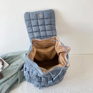 Blue quilted puff backpack with drawstring closure and magnetic flap in casual setting