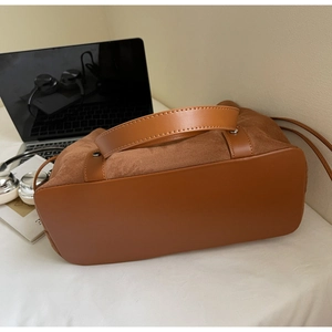 Detail view of brown patchwork suede and leather shoulder bag for commuting with wide base