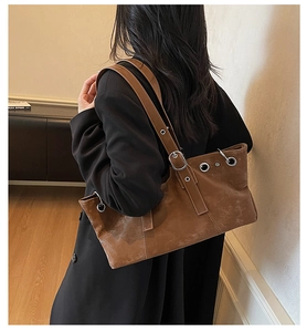 Vue latérale d'un grand sac cabas vintage marron avec œillets métalliques porté par le mannequin