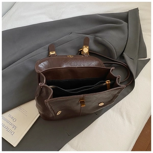 Vintage dark brown oil wax leather backpack with gold buckles on a gray blazer