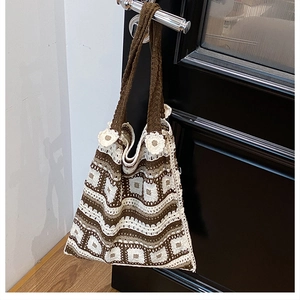 Detail of bohemian knit shoulder bag with vintage geometric patterns and floral accents