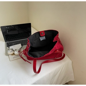 Detail view of large matte red tote bag showing black lining, zip pocket, and brand label