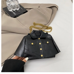 Detail view of a black jacket-shaped crossbody bag with gold buttons and metal chain