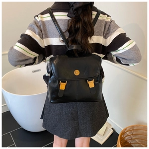 Detail of vintage PU leather backpack with gold buckles and round metallic logo