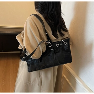 Détail des boucles à rivets et anneaux en métal sur un sac fourre-tout noir en cuir